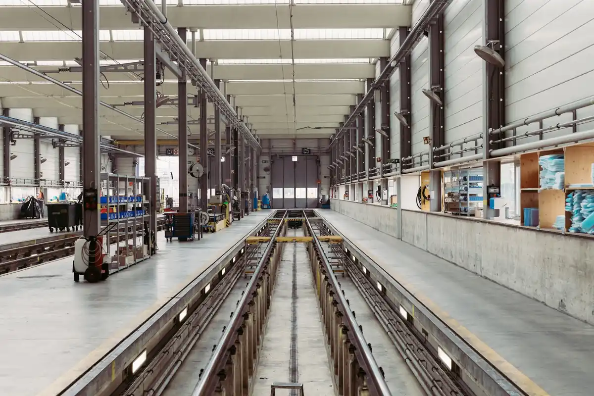 An empty industrial maintenance hall with long parallel service tracks running into the distance under a high roof.