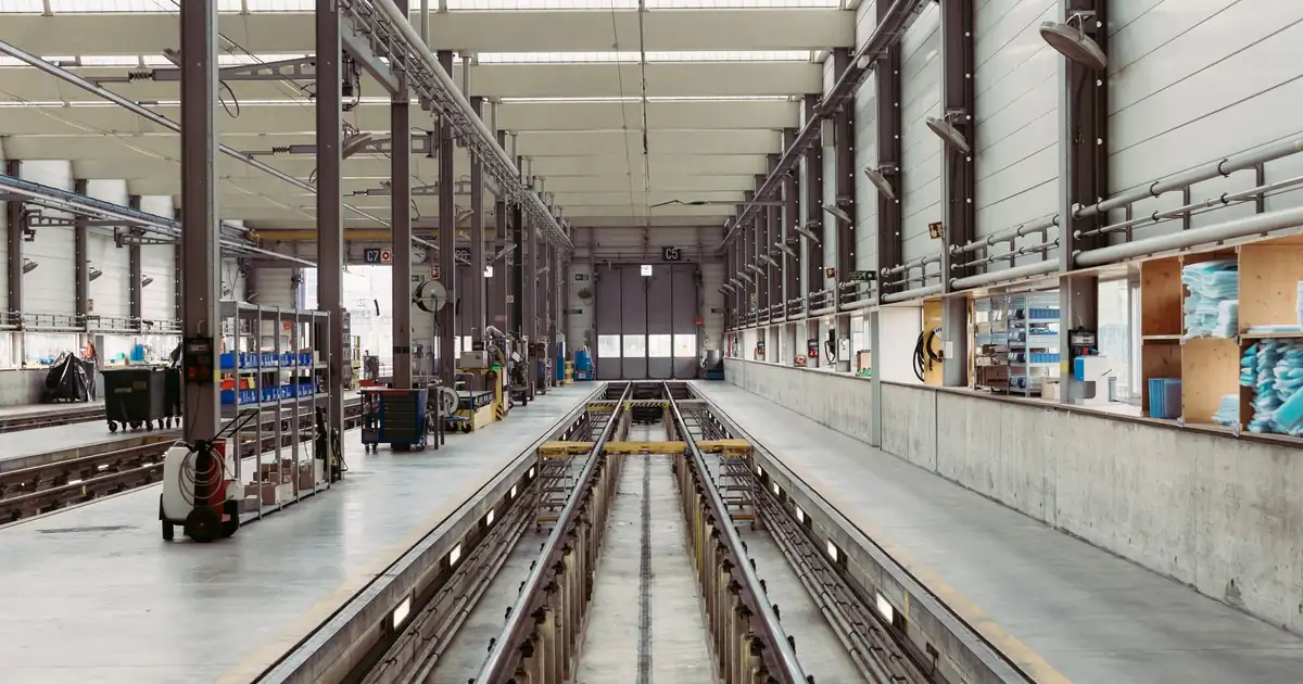 An empty industrial maintenance hall with long parallel service tracks running into the distance under a high roof.