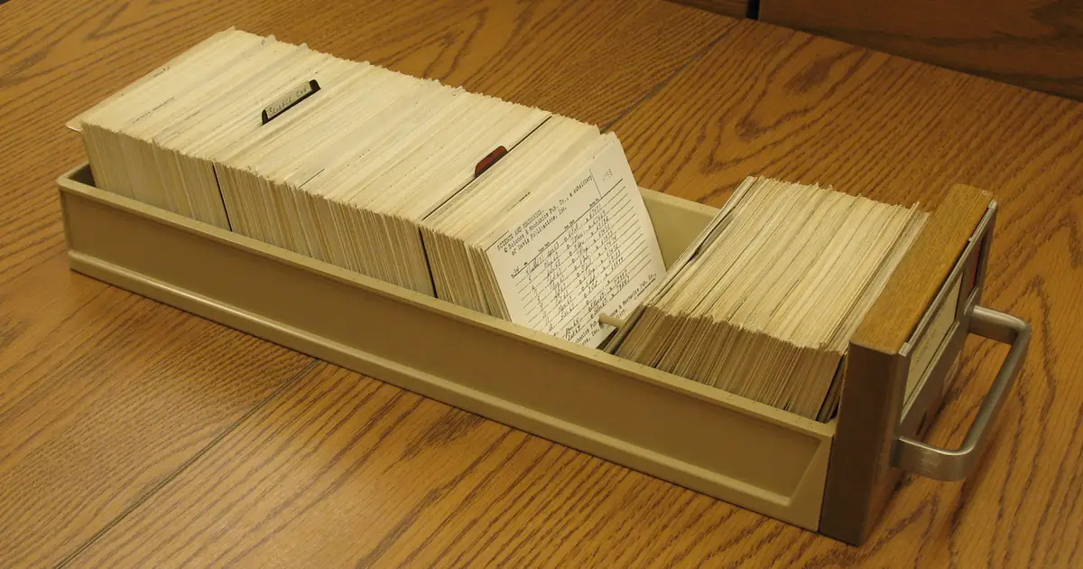 A long library drawer packed with typed index cards and divider tabs, resting on a wooden table.